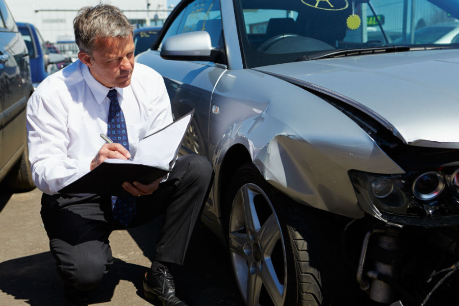 insurance adjuster analyzing damaged car